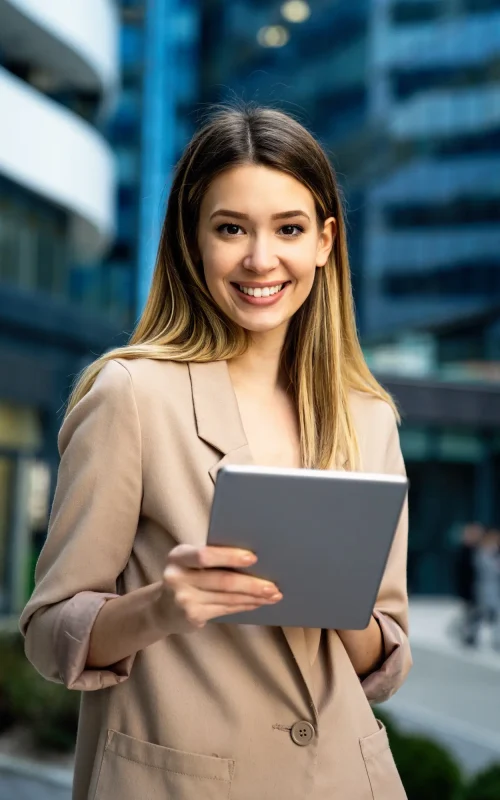 successful-businesswoman-using-a-digital-tablet-while-standing-in-front-of-business-building